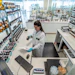 Scientist in lab coat working at bench with shelves of bottles and products in modern laboratory