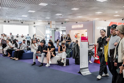 Diverse crowd gathered in modern event space with purple flooring, branded signage, and casual social atmosphere