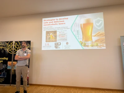Man presenting research on nonalcoholic beer strategies at academic conference with projected slides and institutional logos