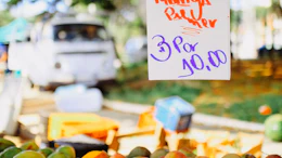 Handwritten price sign for mango pulp at a farmer's market stand with fresh mangoes displayed below