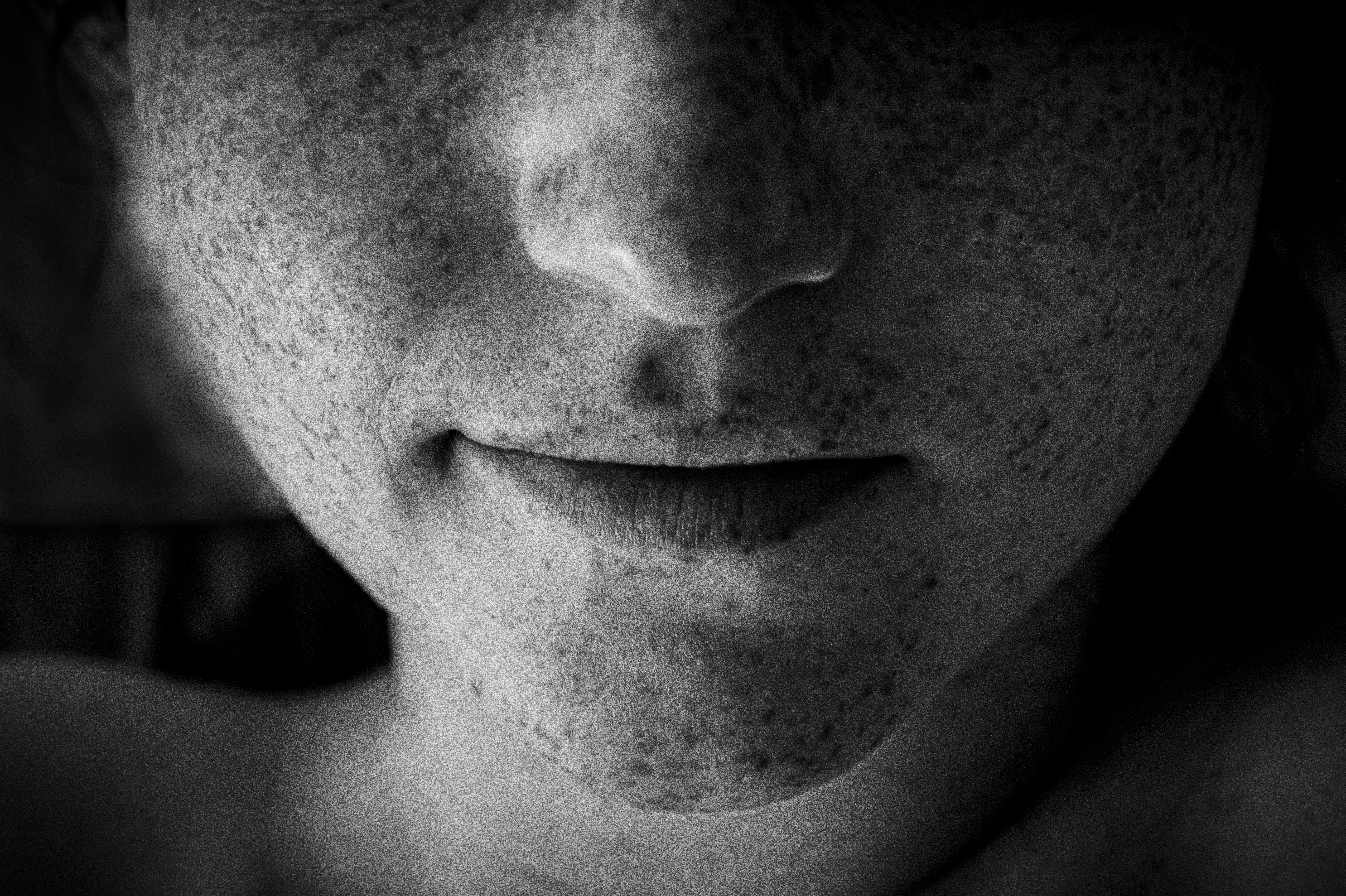 Close-up black and white portrait of lower face showing chin and mouth with freckles