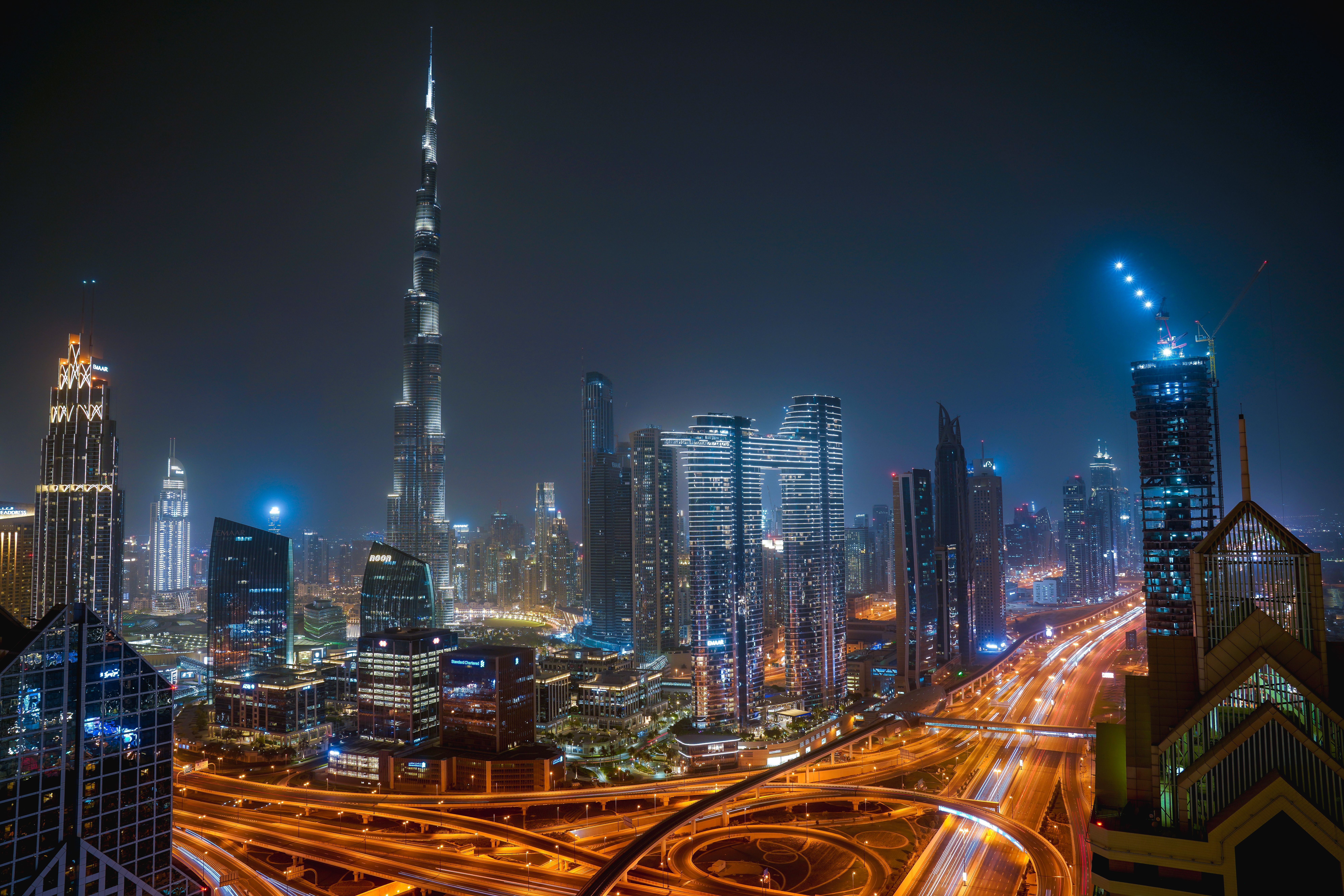 Dubai skyline at night featuring Burj Khalifa and illuminated skyscrapers with busy highway traffic below